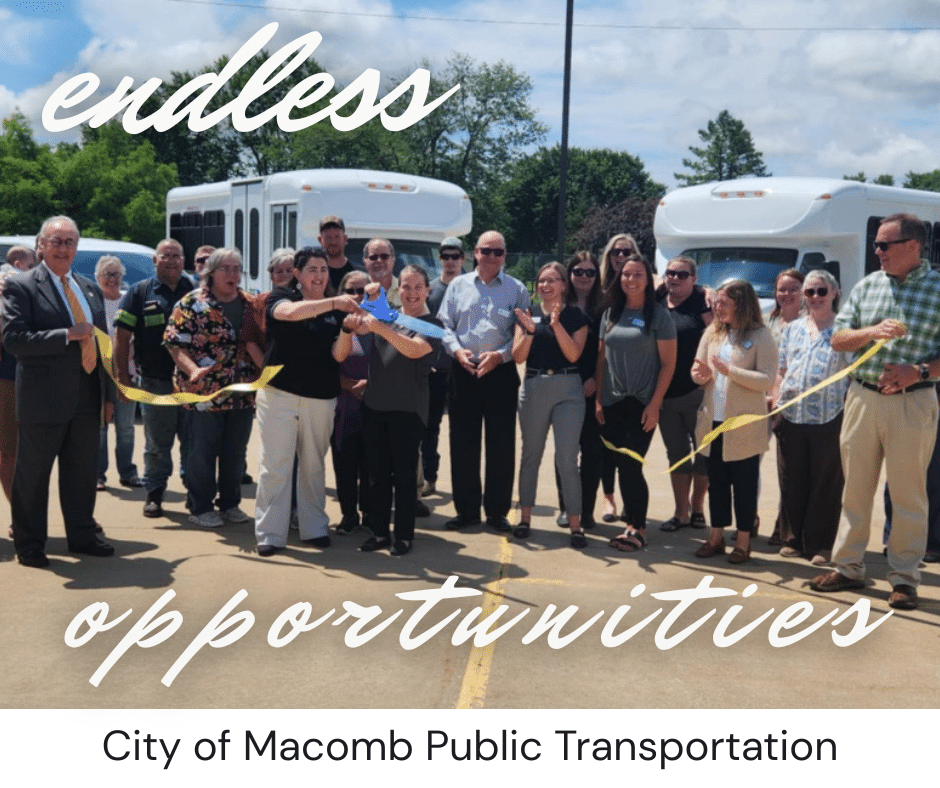 A group of people stand outside, smiling and cutting a yellow ribbon in front of buses. The text reads “endless opportunities” and “City of Macomb Public Transportation.”.